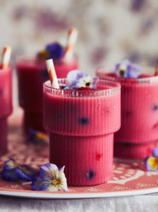 Close up of three glasses of pink smoothie decorated with pansy petals. Close up of three glasses of pink smoothie decorated with pansy petals.
